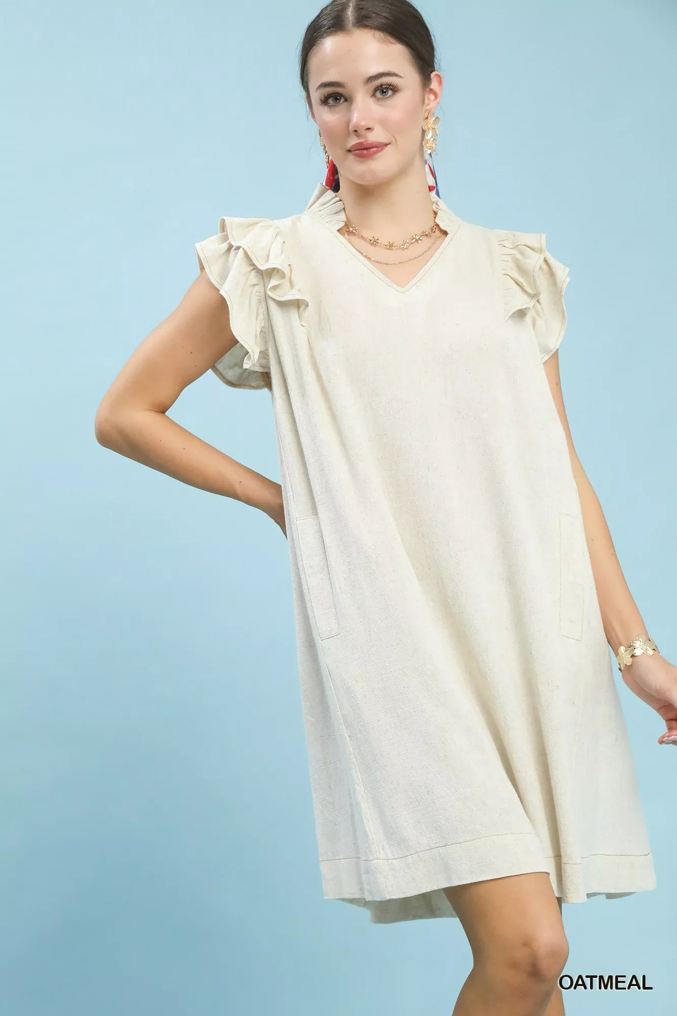 Woman wearing a white dress with ruffled sleeves against a light blue background