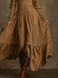 Person wearing a long brown dress with a textured background