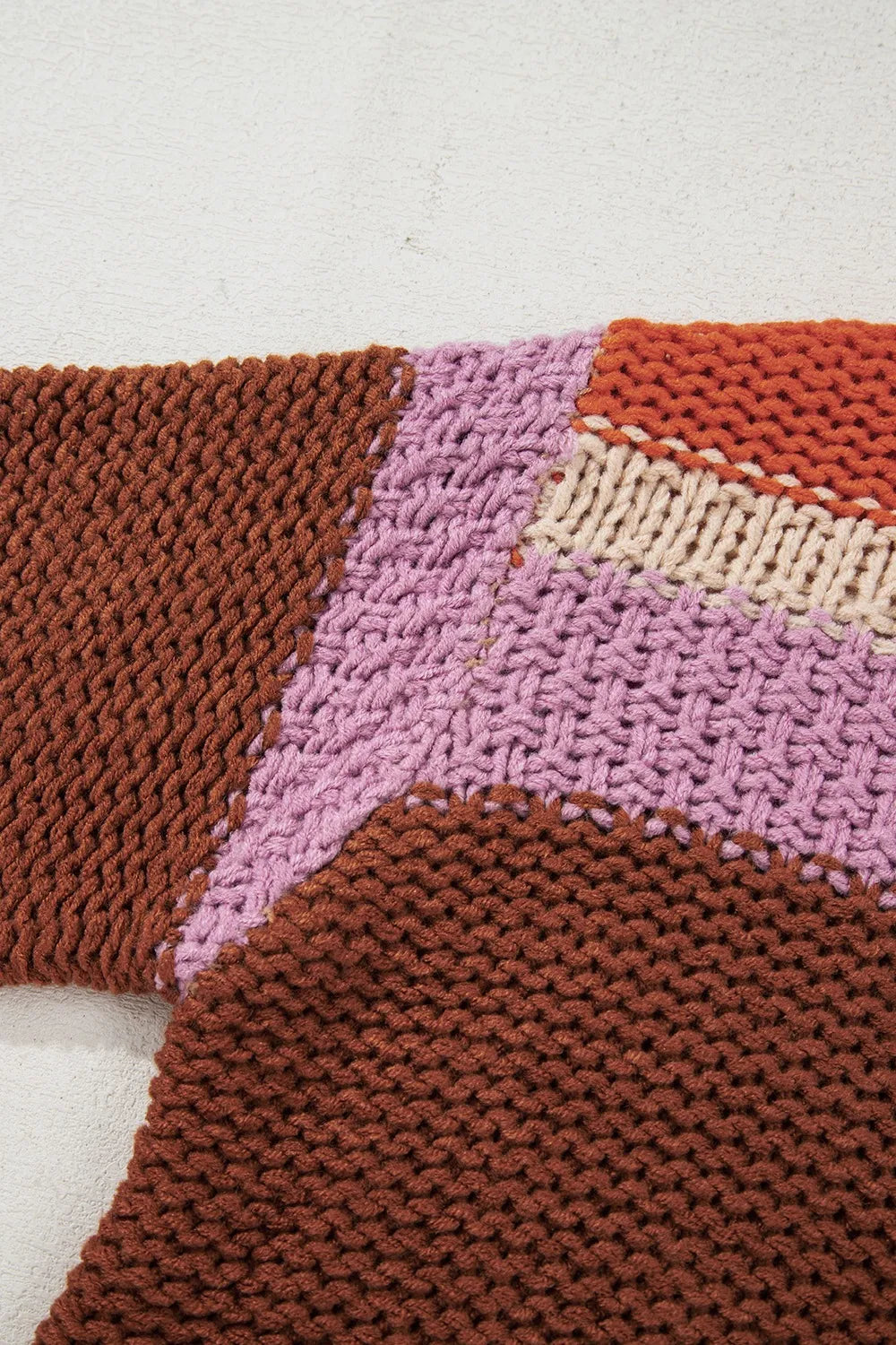 Close-up of a knitted fabric with brown, pink, and beige pattern on a white background