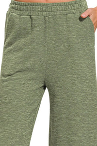 Green sweatpants worn by a person on a white background