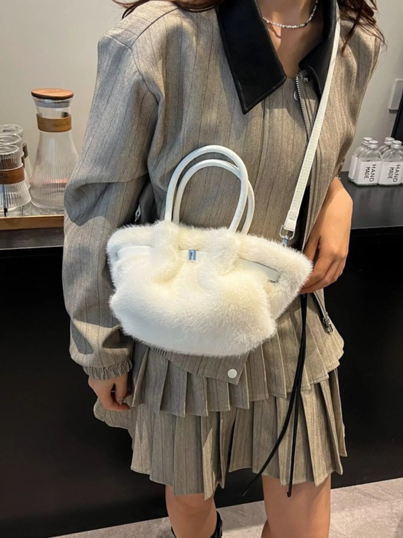 Person holding a white fluffy handbag indoors