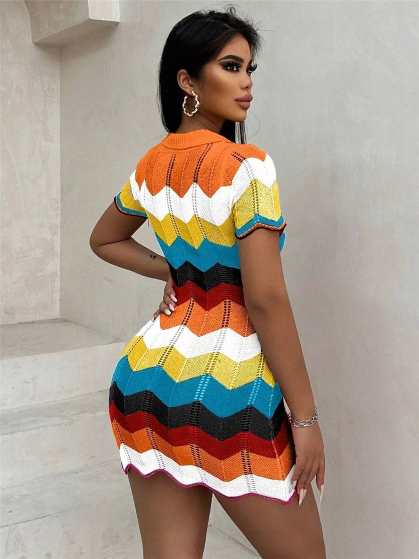Woman wearing a colorful striped dress against a neutral background