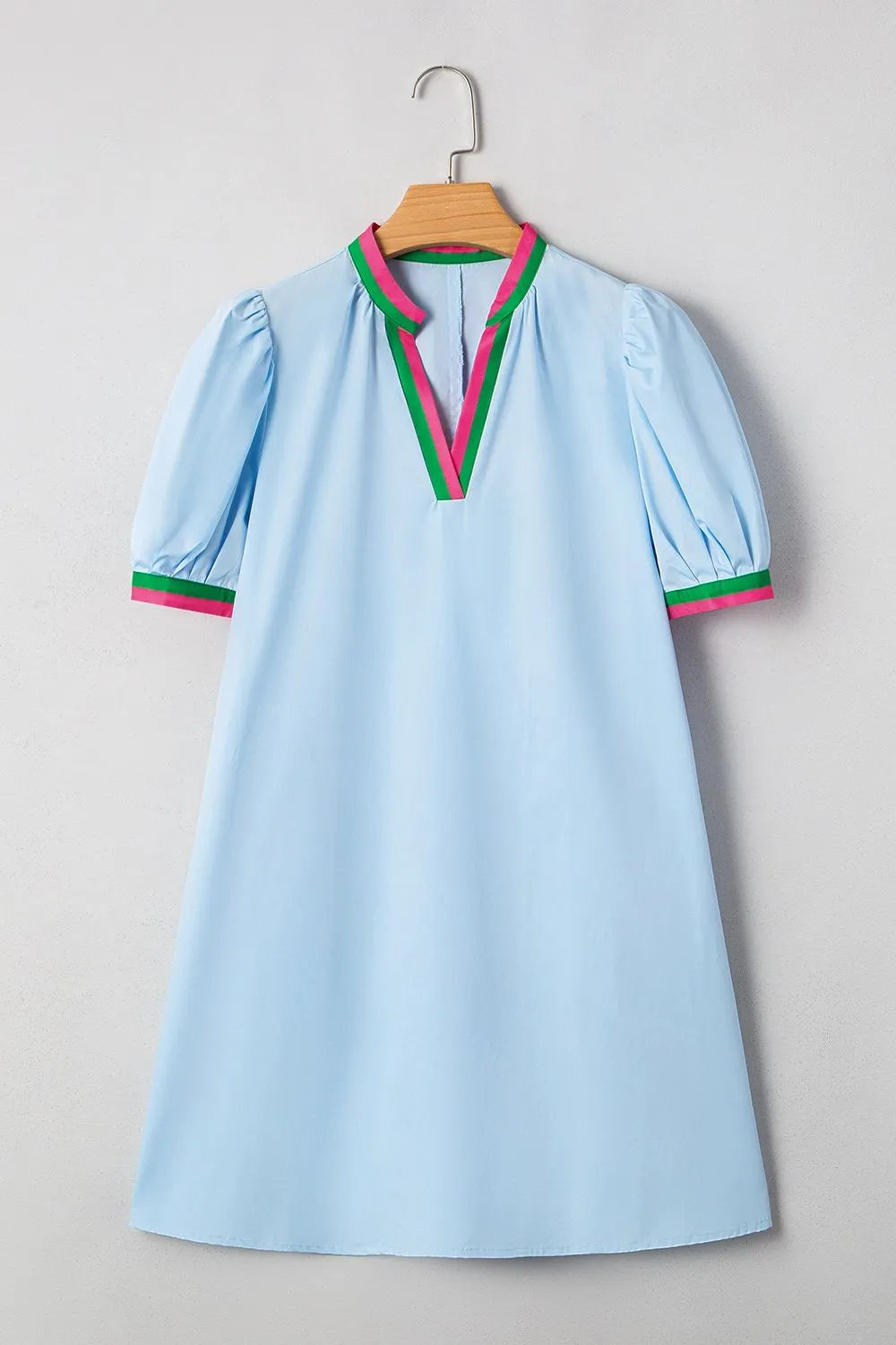 Light blue dress with red and green accents on a hanger against a gray background