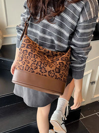 Person wearing a striped sweater and holding a leopard print bag in a kitchen.
