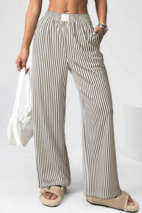 Person wearing striped pants holding a white bag on a plain background