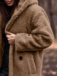 Brown teddy coat worn by a person with a blurred natural background
