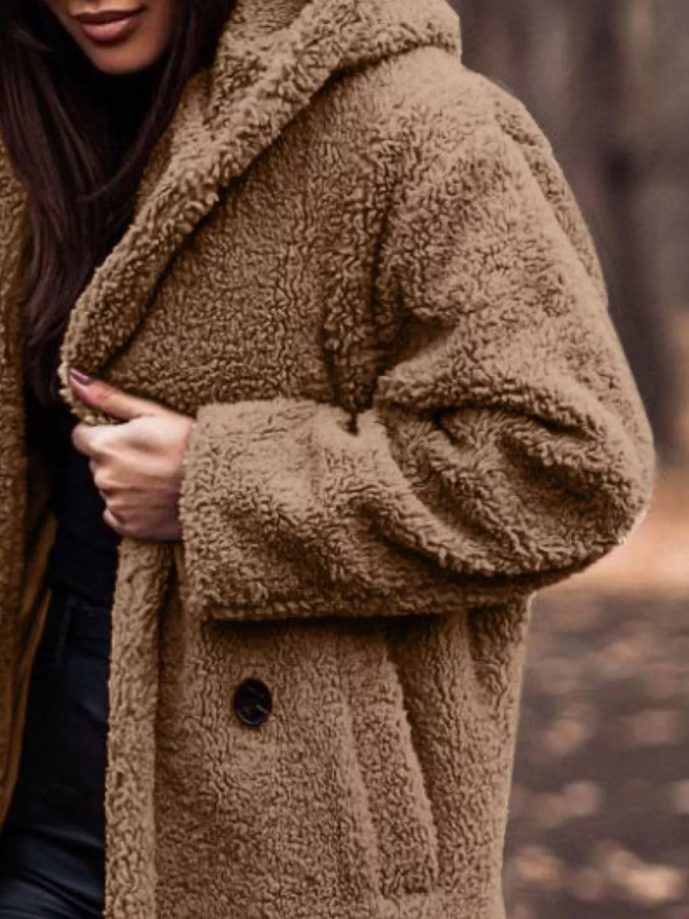 Brown teddy coat worn by a person with a blurred natural background