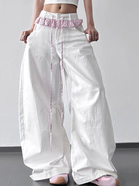 White wide-leg pants with pink trim worn by a person on a plain background
