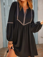 Black dress with intricate detailing worn by a person, standing against a neutral background.