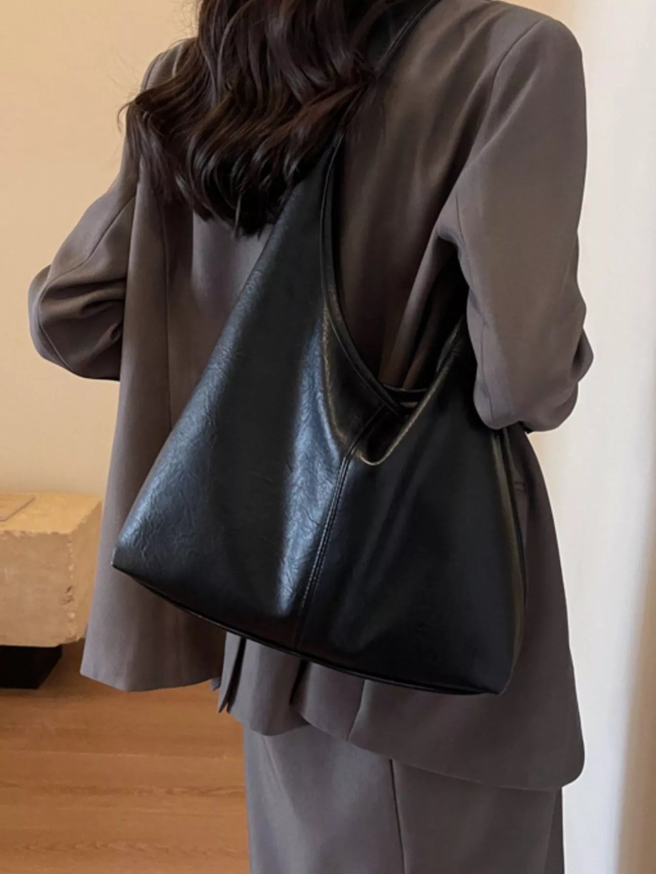 Person wearing a dark gray coat with a black leather bag over their shoulder.