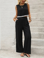 Woman wearing a black sleeveless top and wide-leg pants on concrete steps.