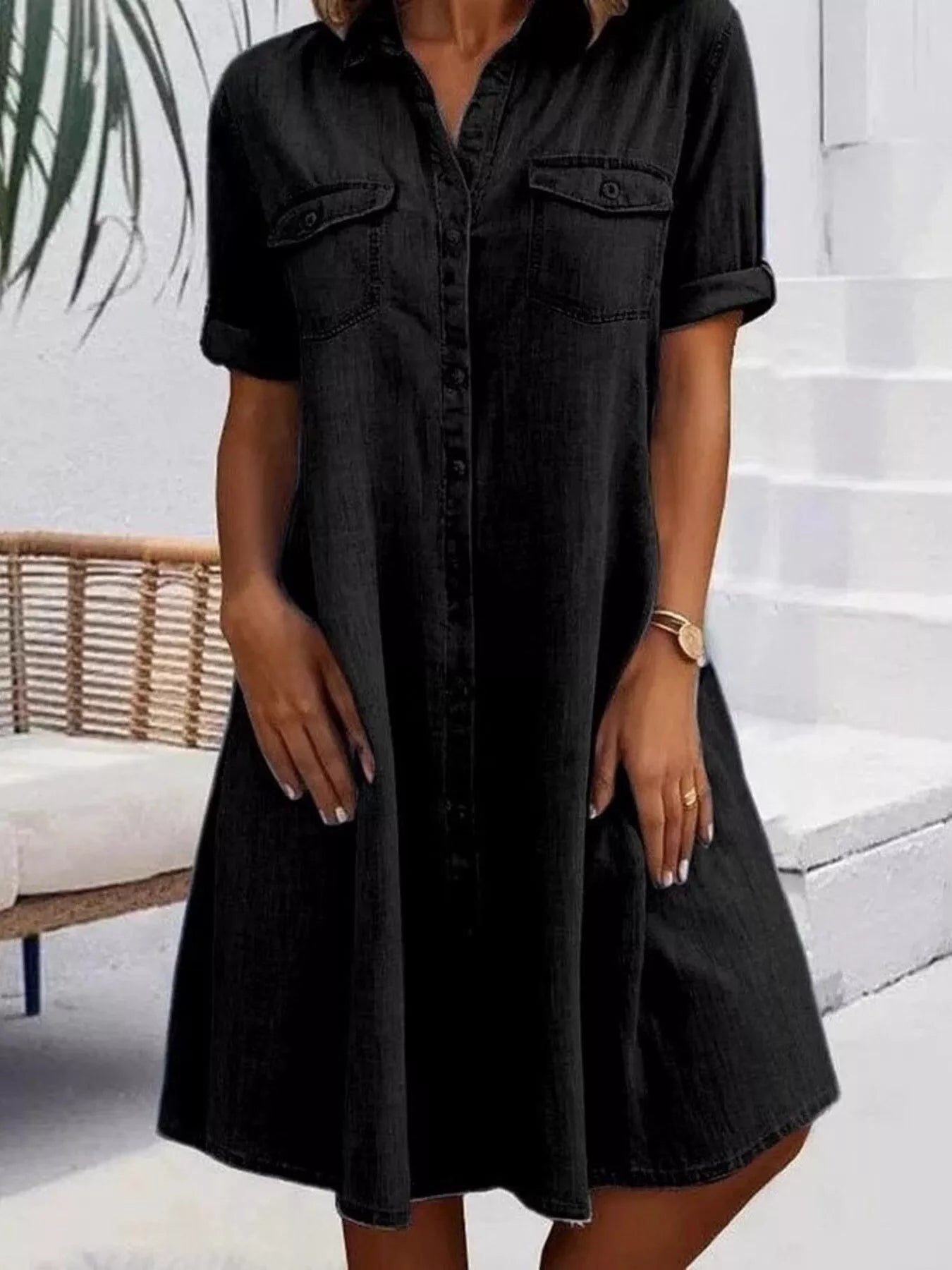Woman wearing a black dress standing on a white staircase.