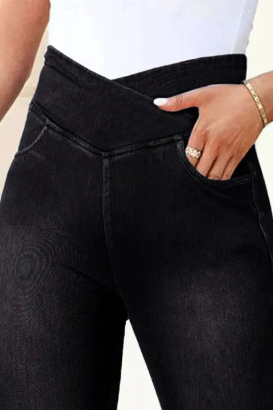 Person wearing black jeans with a plain background