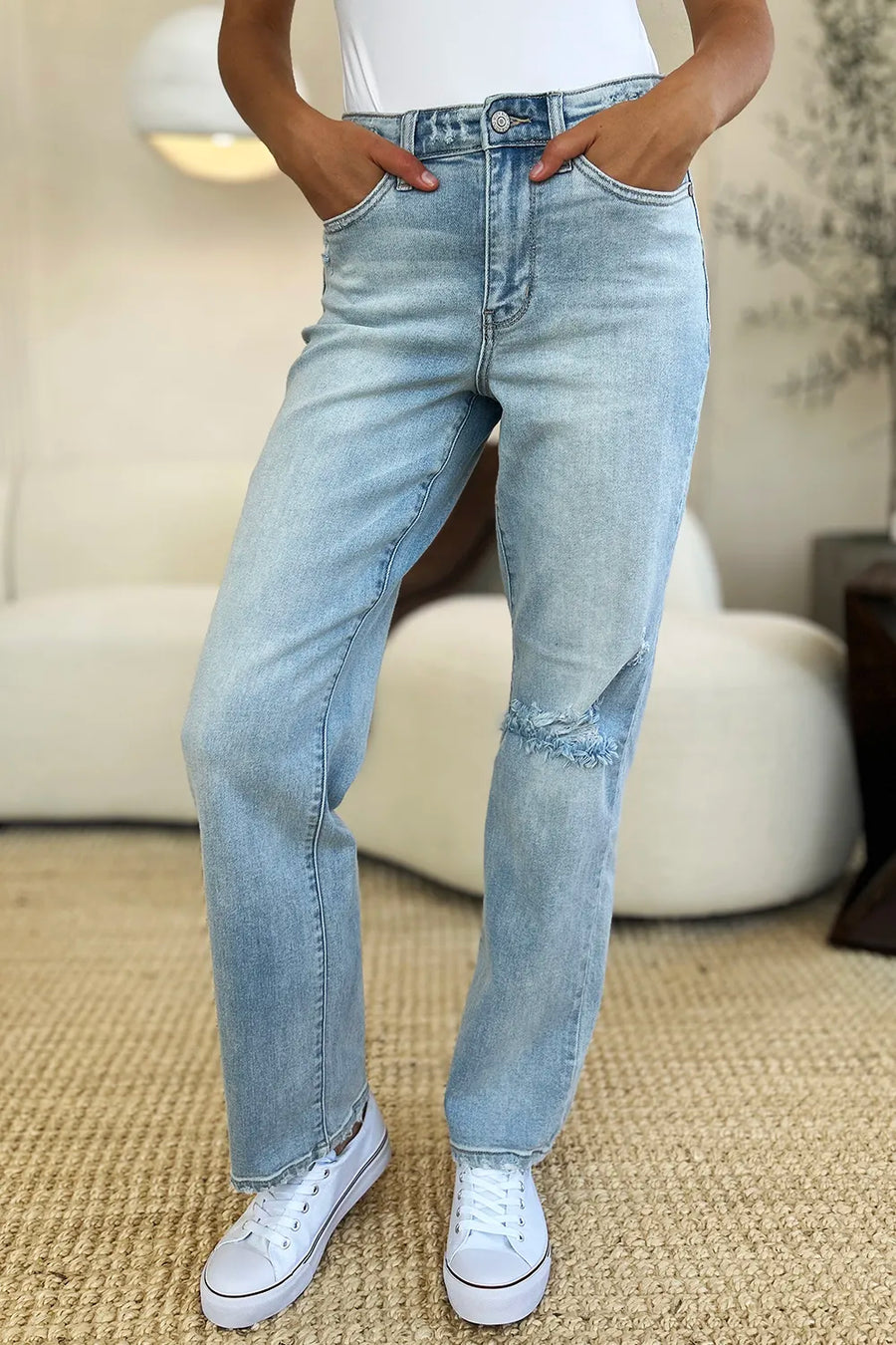 Person wearing light blue jeans and white sneakers in a casual setting
