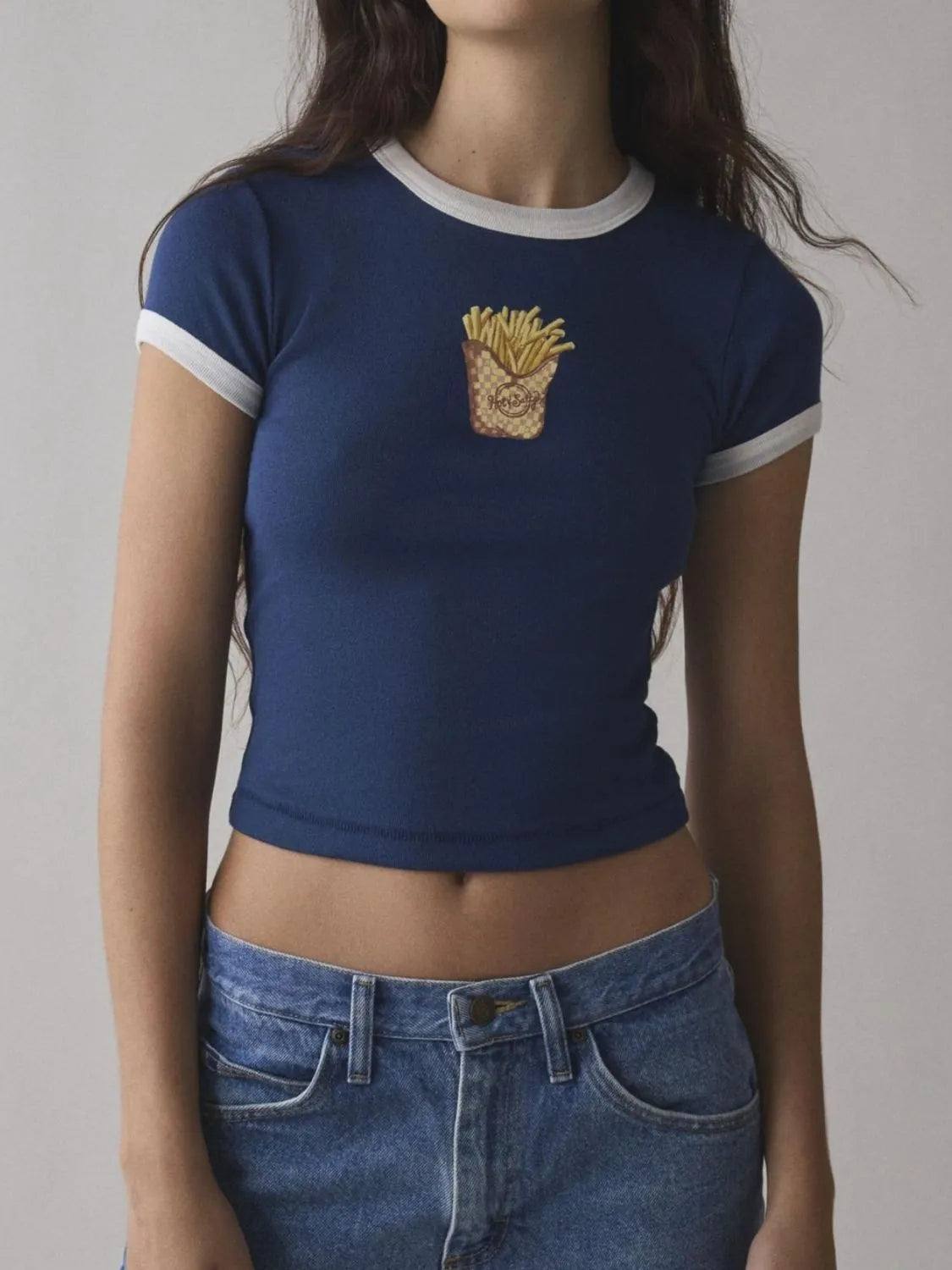 Person wearing a blue t-shirt with a graphic design on a plain background