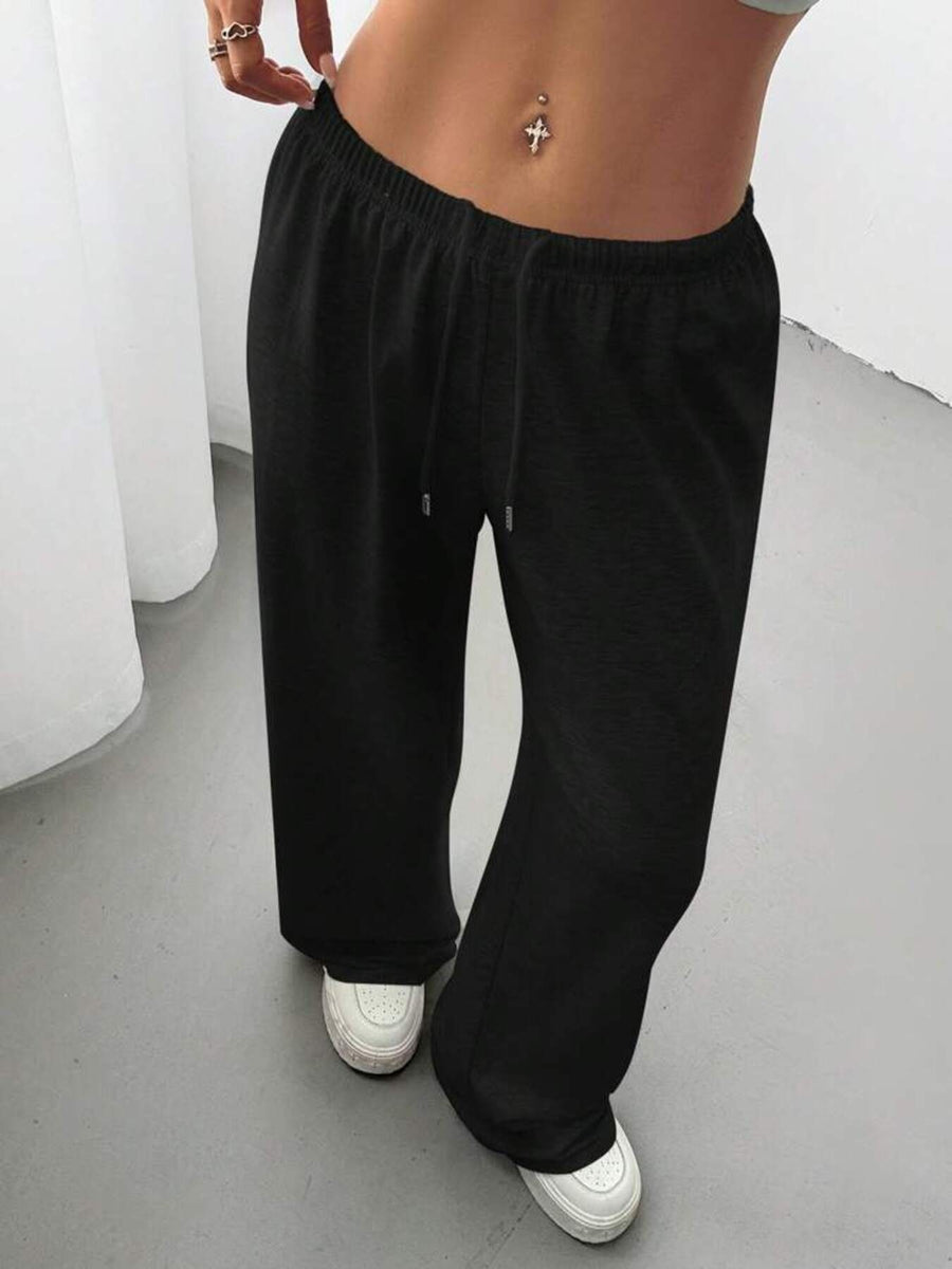 Person wearing black pants and white shoes on a plain background