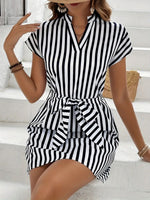 Woman wearing a black and white striped dress sitting on a white staircase.
