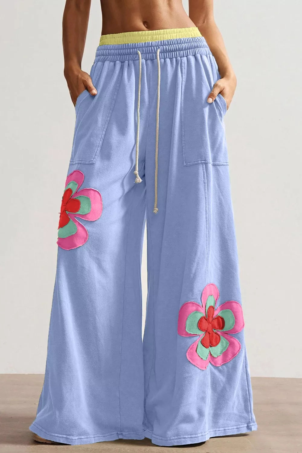 Light blue pants with pink floral designs on a plain background