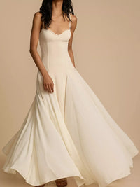Woman wearing a flowing white dress against a beige background