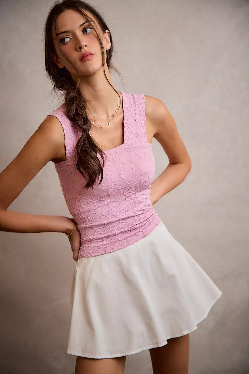Woman wearing a pink top and white skirt against a plain background