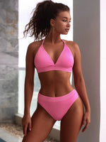 Woman wearing a pink bikini set against a neutral background