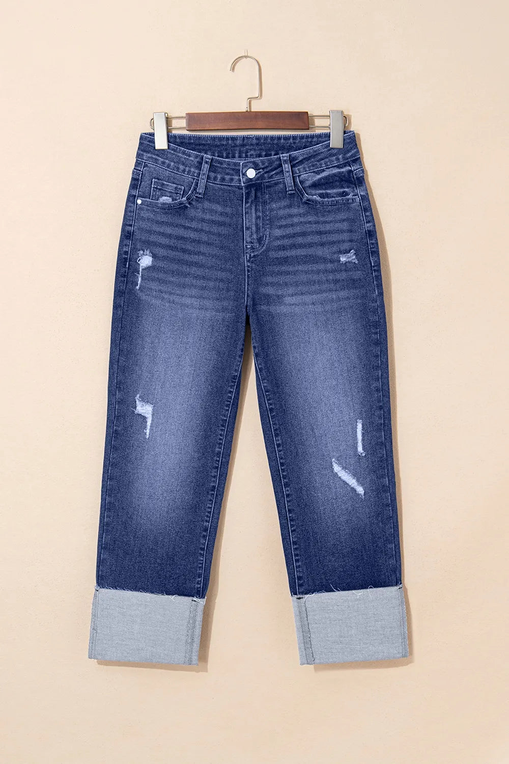 Blue jeans with distressed details on a beige background