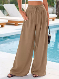 Person wearing tan wide-leg pants by a poolside