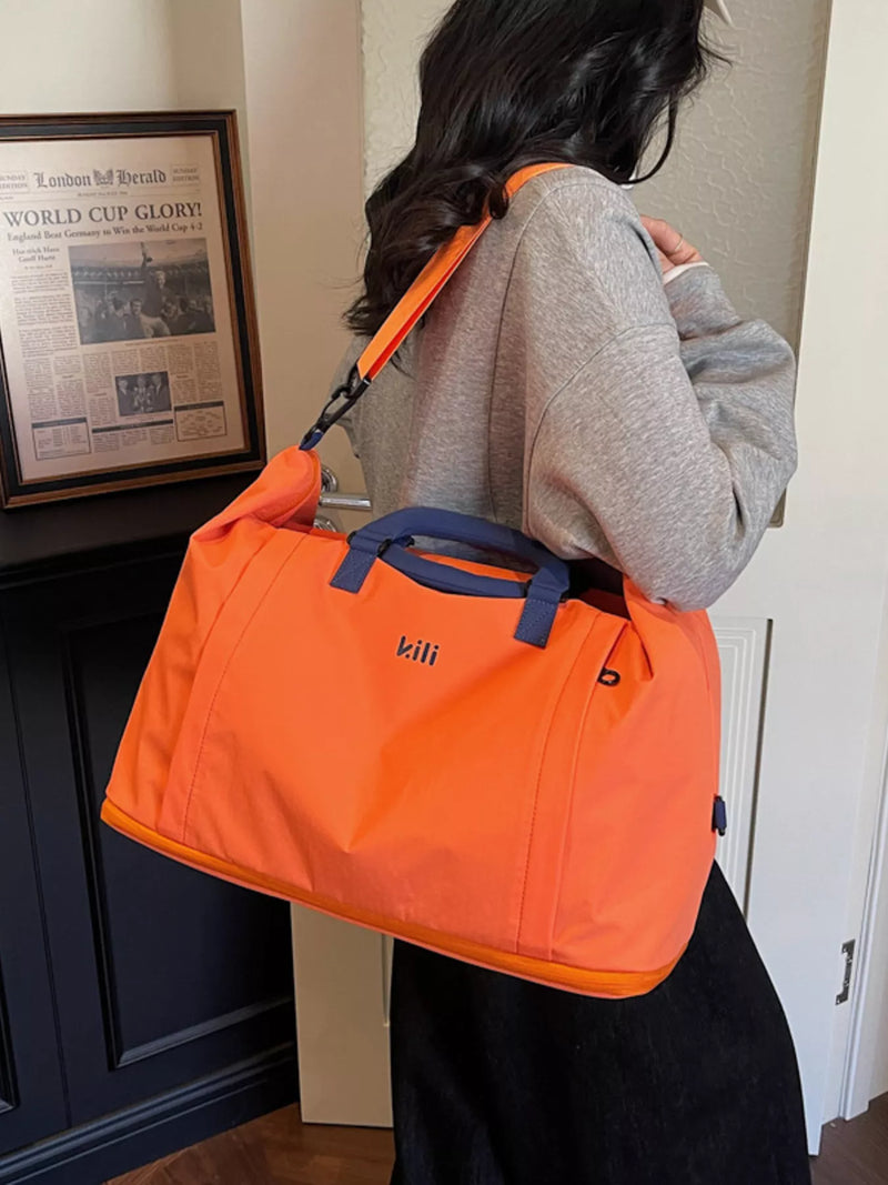 Person carrying an orange bag with 'kii' branding indoors.