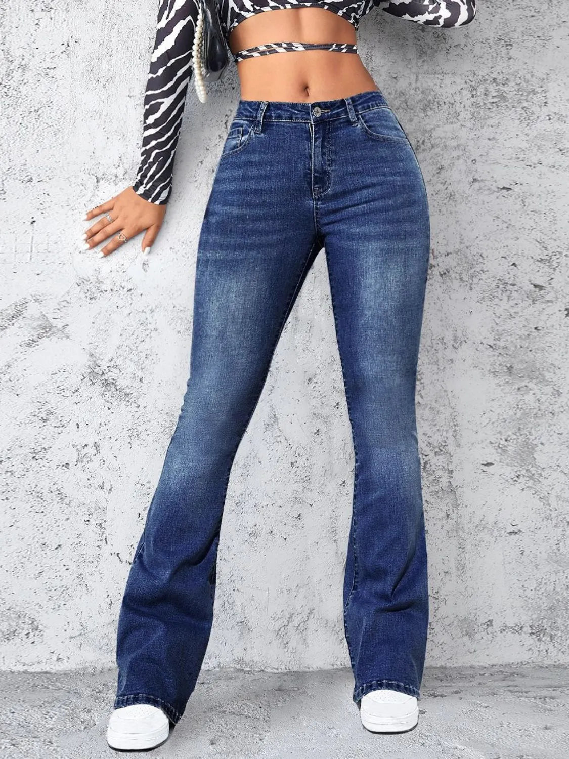 Person wearing blue jeans against a gray concrete wall