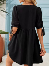Black dress with puff sleeves worn by a person, with a blurred background