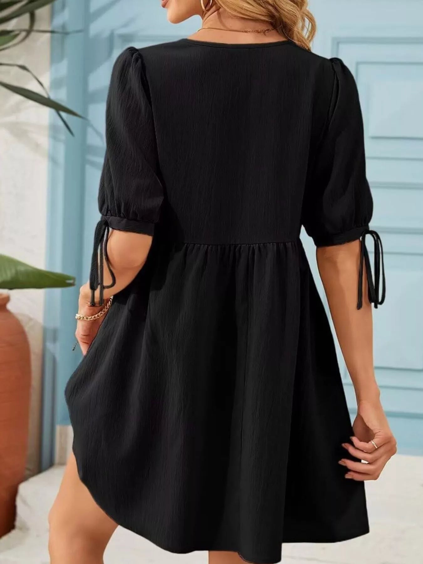 Black dress with puff sleeves worn by a person, with a blurred background