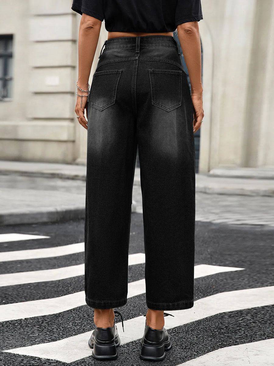 Person wearing black wide-leg jeans standing on a zebra crossing with a building in the background.