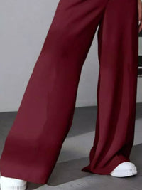 Maroon wide-leg pants worn by a person on a gray background