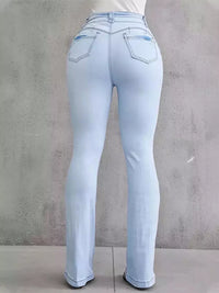 Light blue jeans worn by a person against a gray concrete wall.