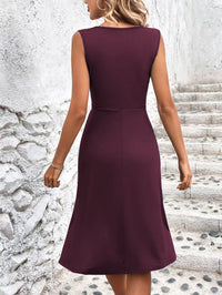 Woman wearing a burgundy dress standing on stone steps with a textured wall background