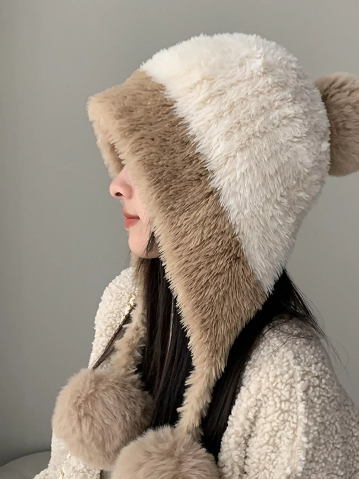 Person wearing a fluffy hooded coat with a neutral background