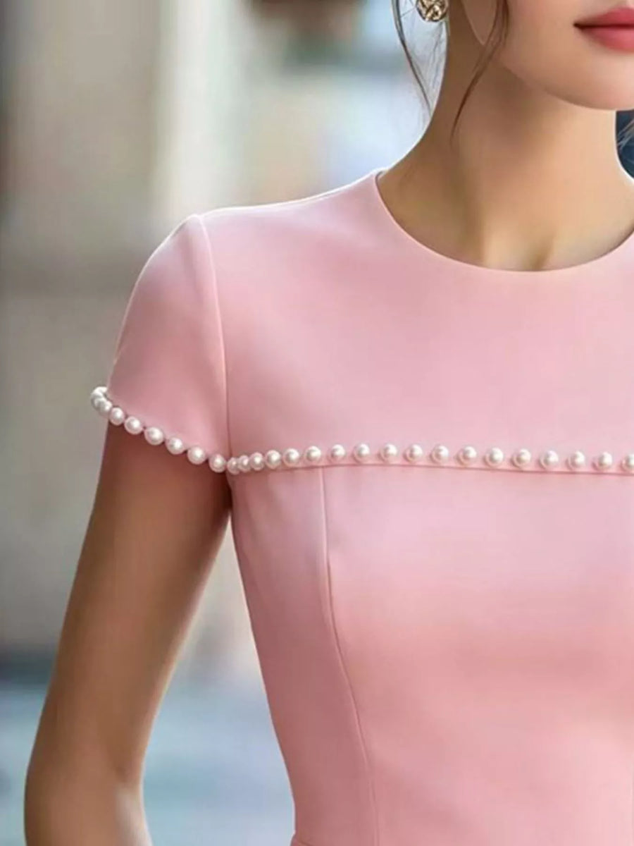 Close-up of a pink dress with pearl details on a blurred background