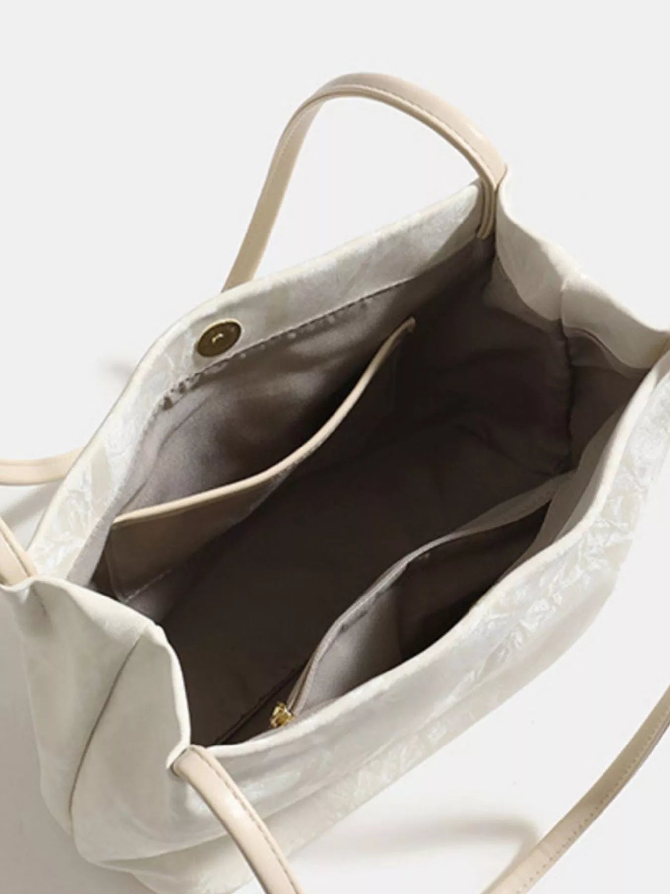 Close-up of a beige handbag with a zipper on a light background