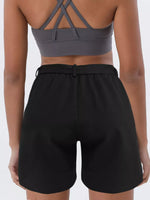 Person wearing a gray sports bra and black shorts on a white background