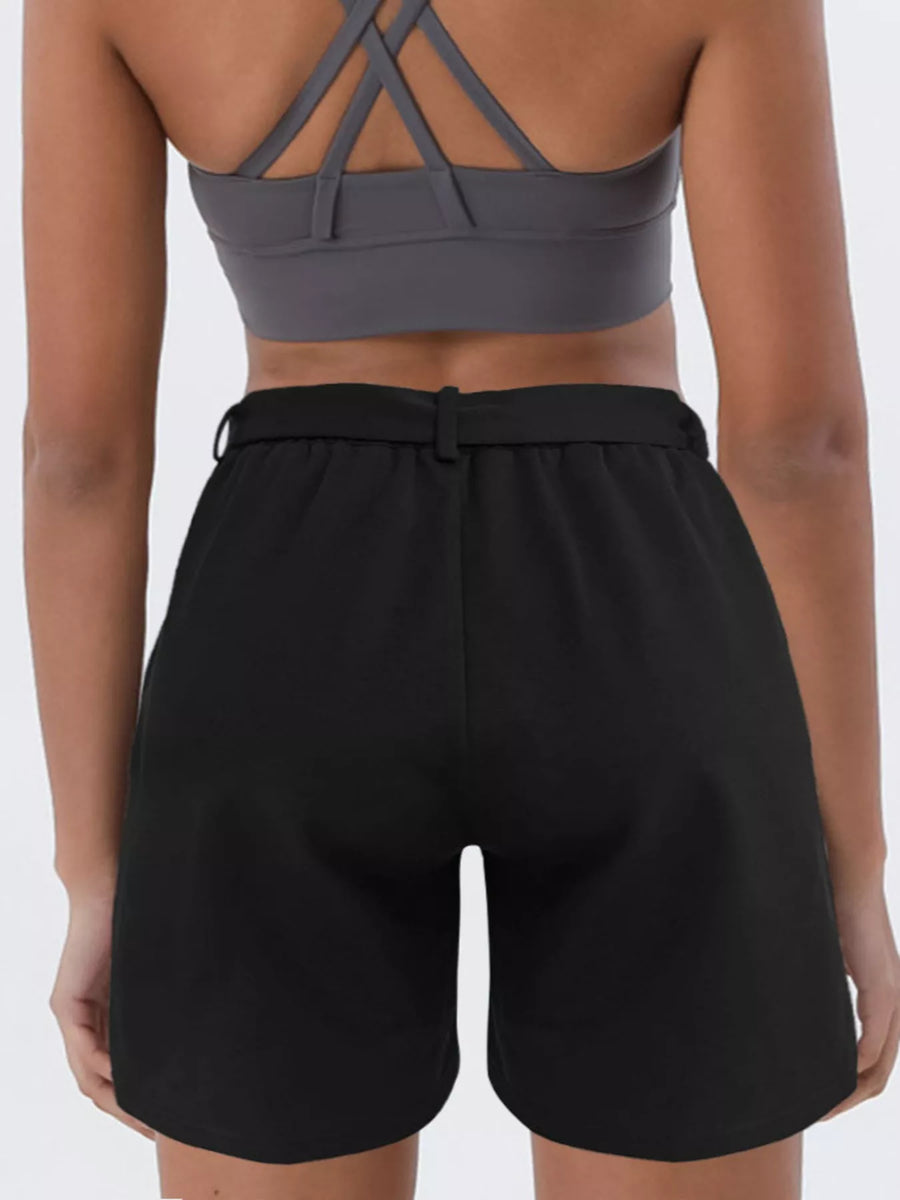 Person wearing a gray sports bra and black shorts on a white background