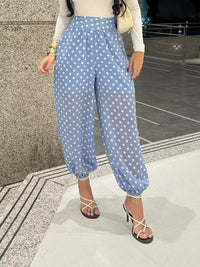 Person wearing blue polka dot pants standing on a street.