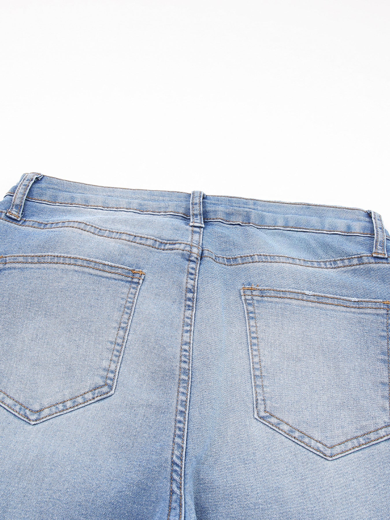 Close-up of light blue denim jeans on a white background
