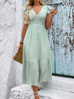 Woman wearing a light green dress against a textured wall.
