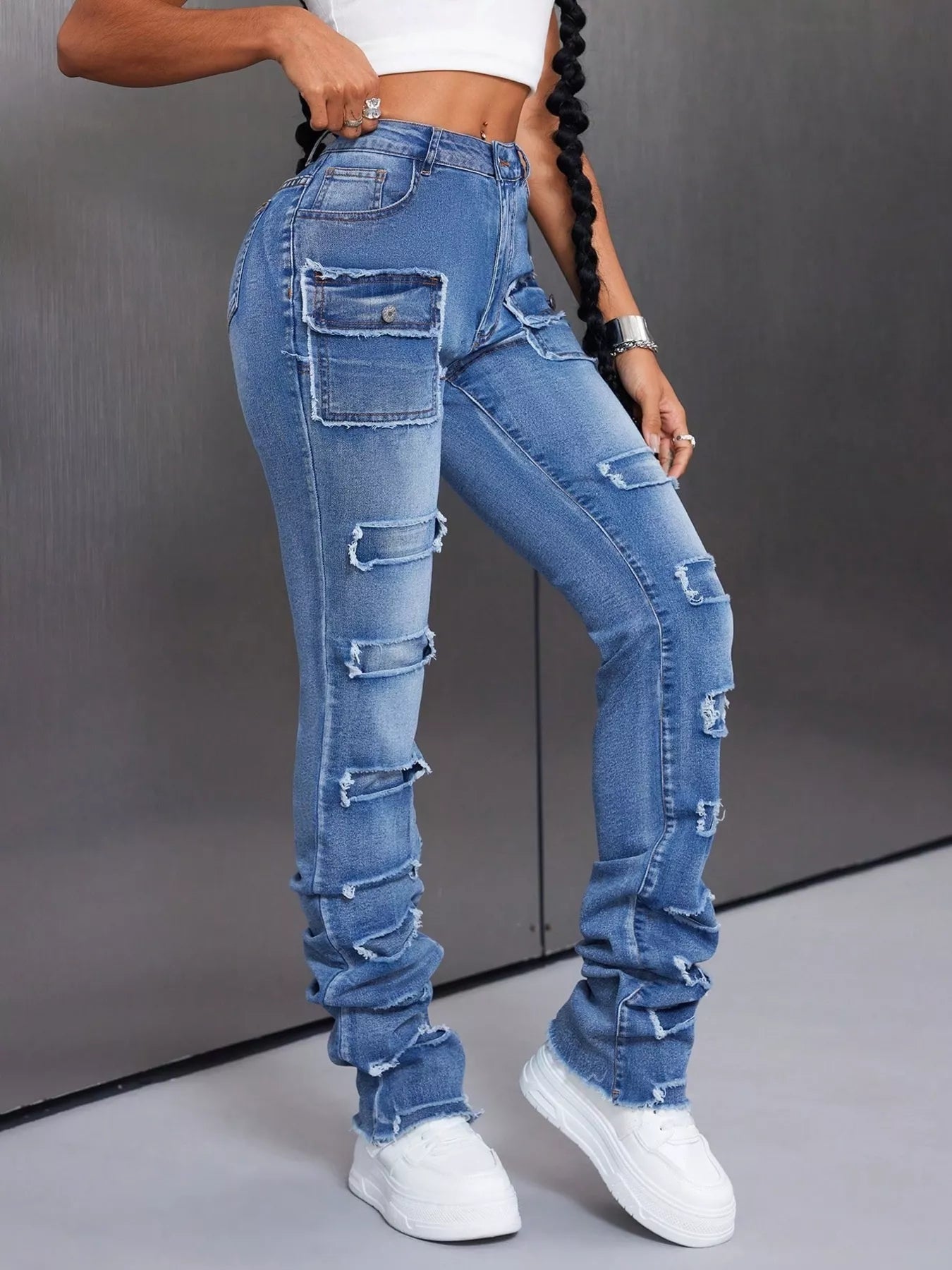 Person wearing high-waisted, distressed blue jeans with a gray background