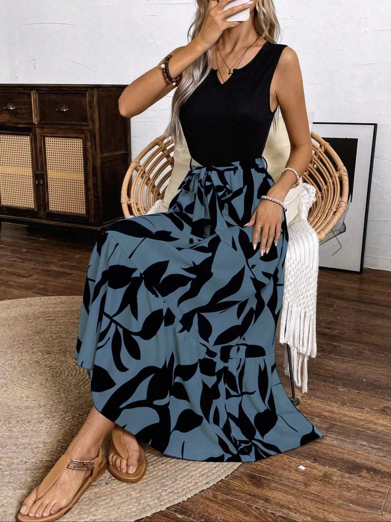 Woman sitting on a chair wearing a black top and blue patterned skirt.