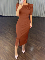 Woman wearing a brown dress with a floral detail in an indoor setting.