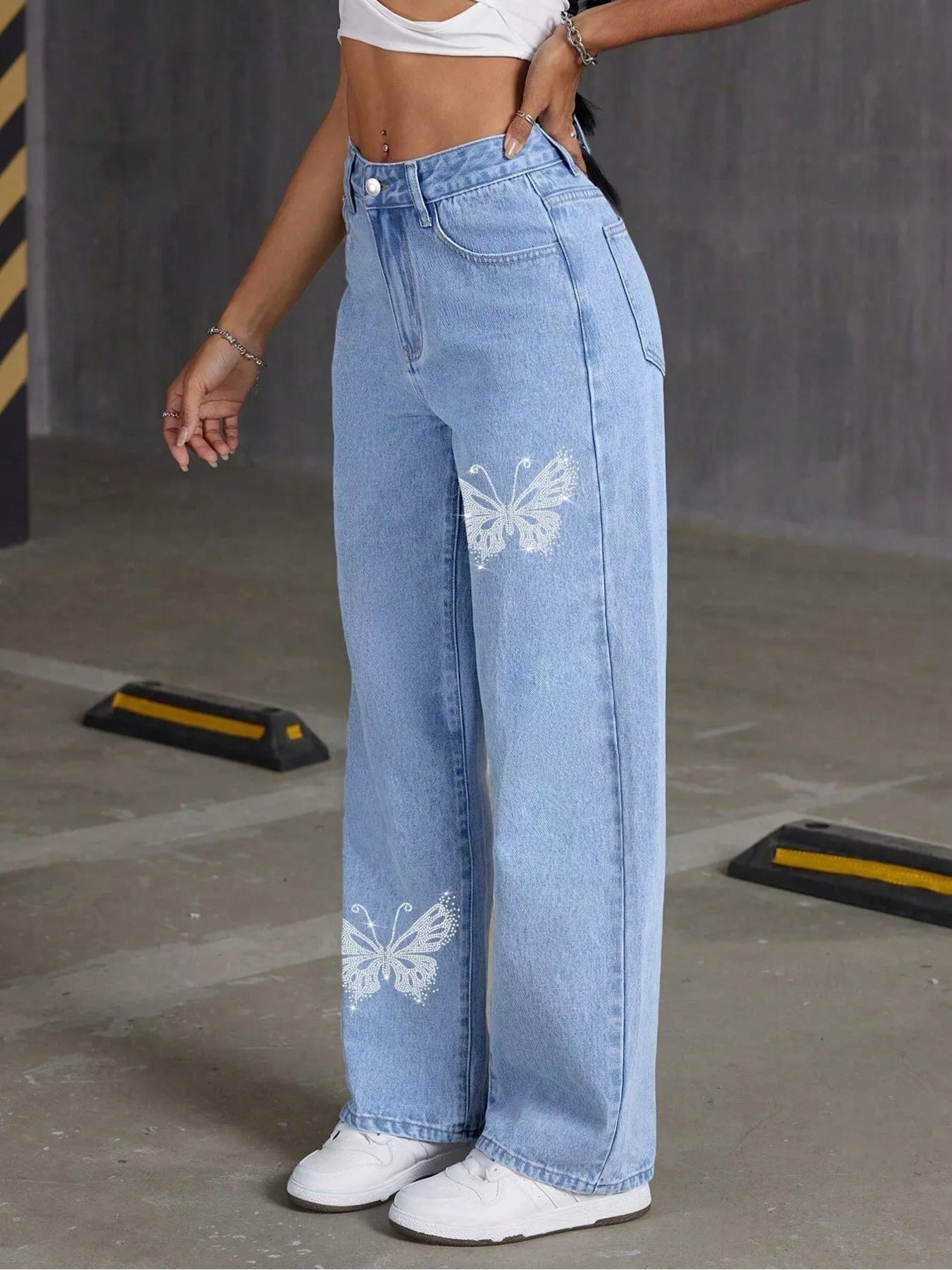Person wearing light blue jeans with butterfly designs in an urban setting