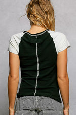 Person wearing a black and white sleeveless top with a gray background