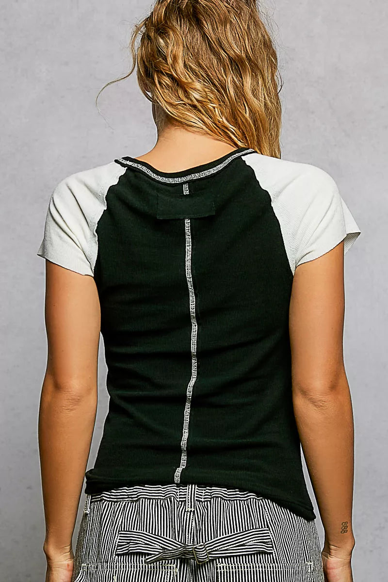 Person wearing a black and white sleeveless top with a gray background
