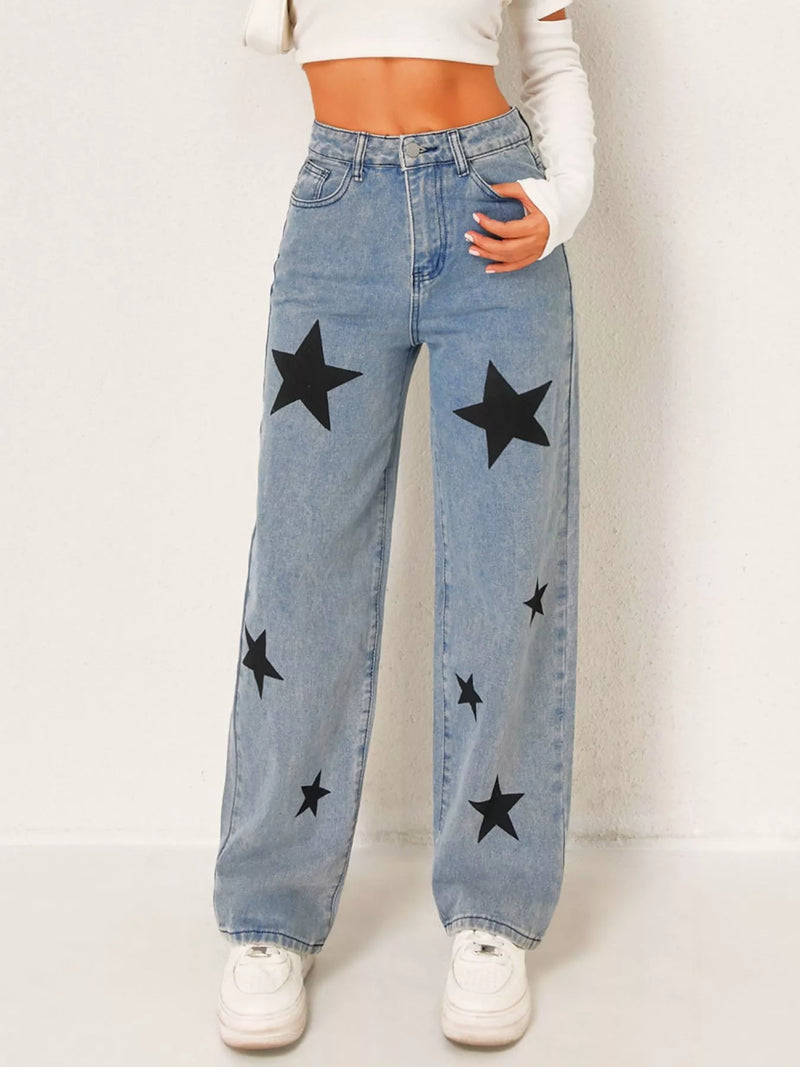 Blue jeans with black star patterns worn by a person on a white background